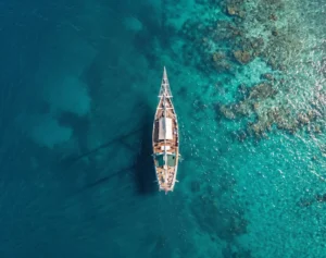 Aerial view of a traditional phinisi wooden ship sailing the turquoise waters of Indonesia